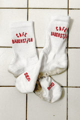Wien Streetwear Socken weiß mit rotem Cafe Bauchstich Schriftzug, GKBS Logo auf Sohle, auf Fliesenboden