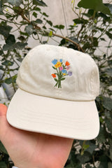 Wien Streetwear Dad Cap in Creme mit bunter Blumenstrauß-Stickerei, Seitenansicht auf Hand gehalten