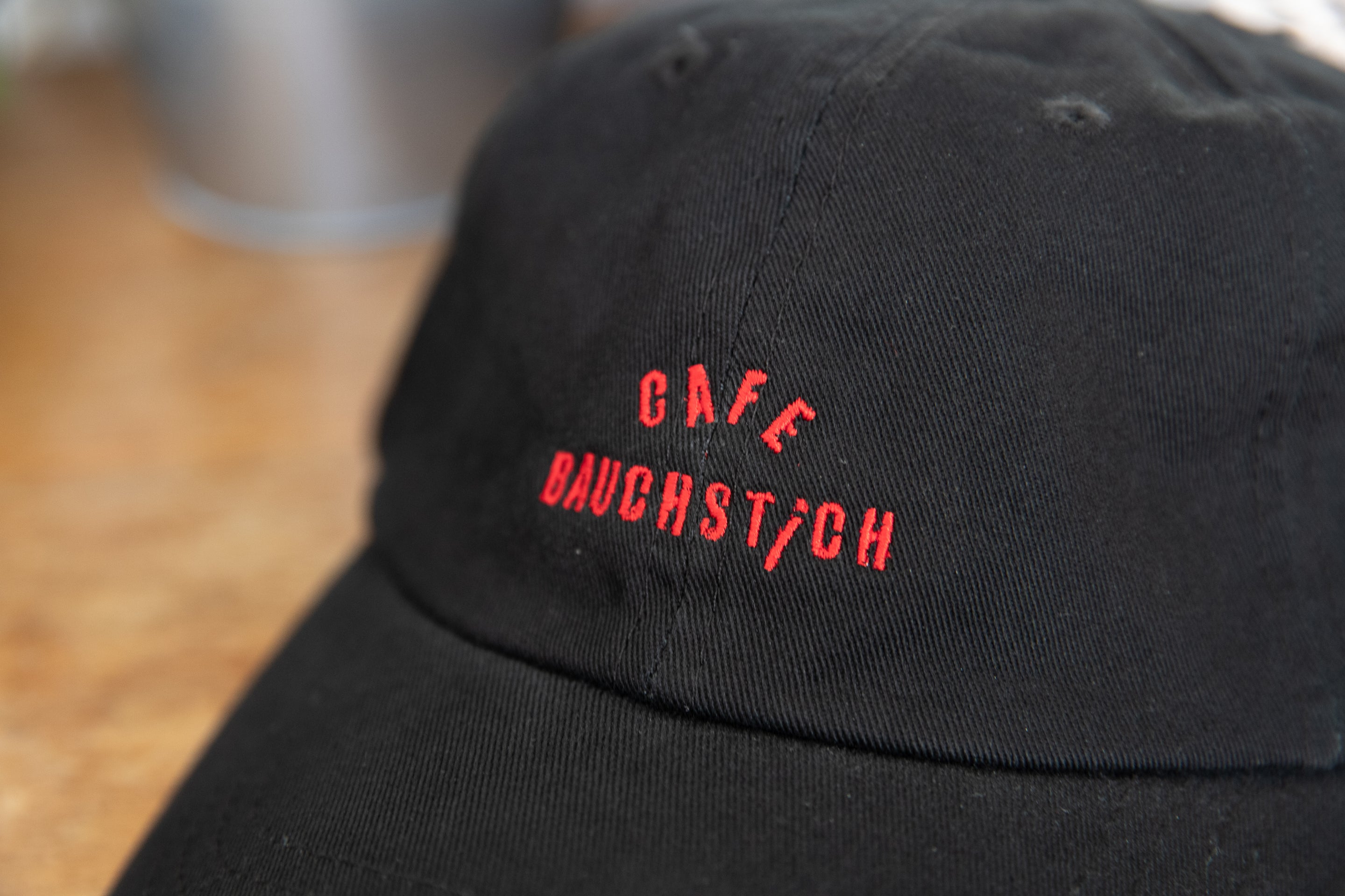 Detailaufnahme roter Cafe Bauchstich Stickerei auf schwarzer Baumwoll Dad Cap, Wien Streetwear