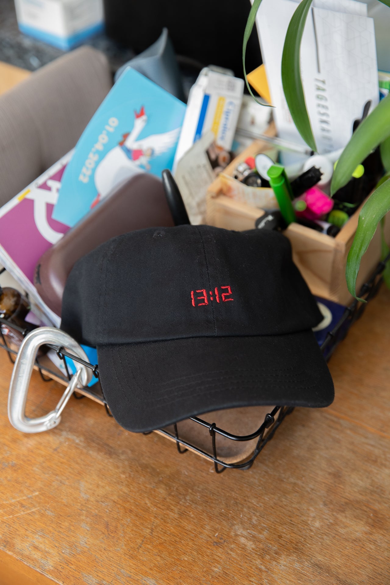 Schwarze Dad Cap mit rot gestickter 13:12 LED-Anzeige vorne, liegt in Drahtkorb – Wien Streetwear