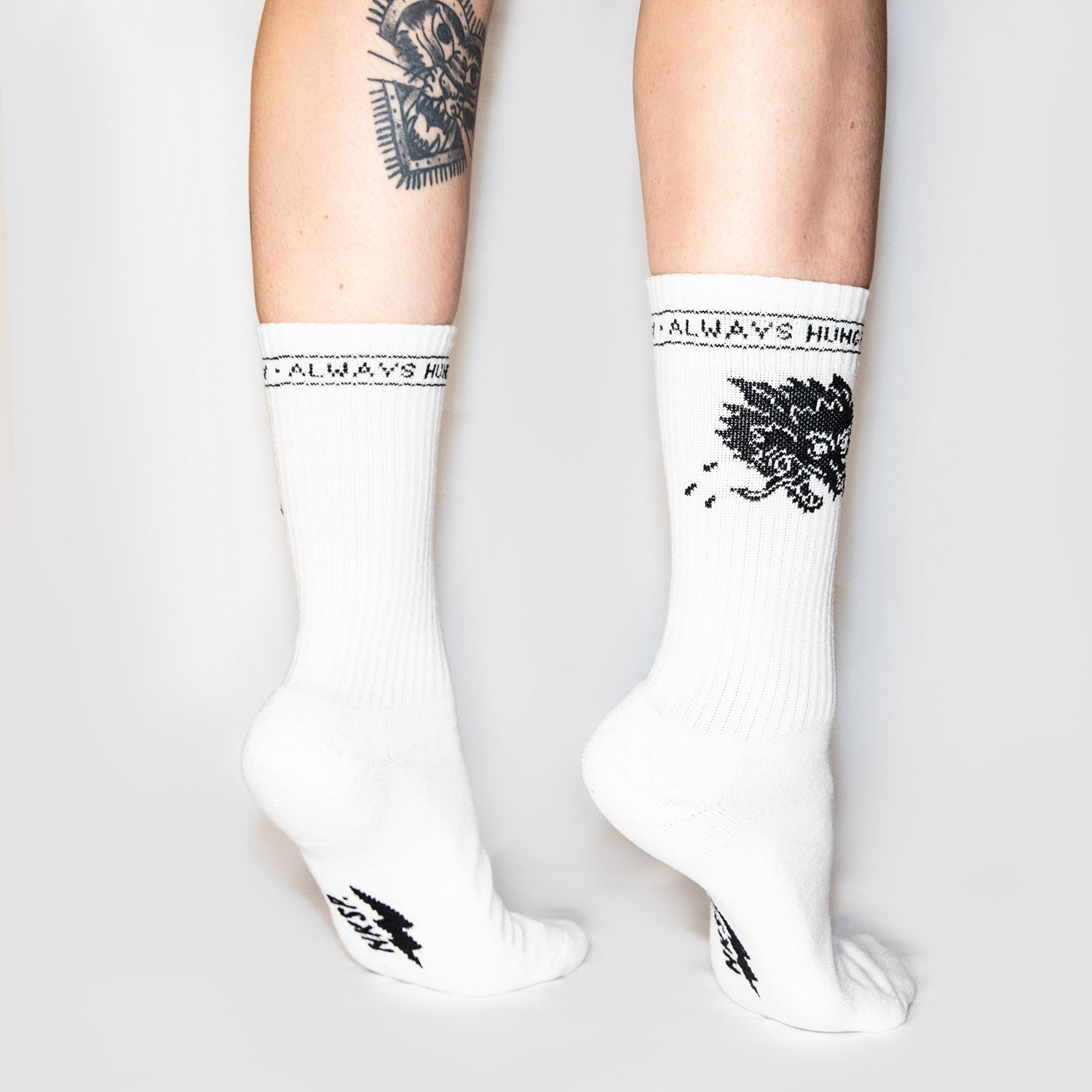 Always Hungry Socken Weiß von NKSP – eingestrickter Wolfskopf und Schriftzug am Schaft, getragen