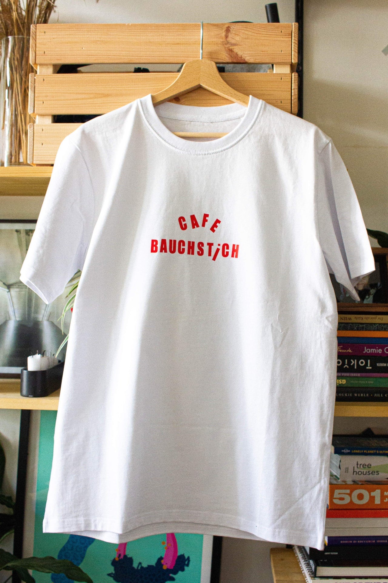 Weißes Loose Fit T-Shirt auf Bügel, roter CAFE BAUCHSTICH Schriftzug vorne, Wien Streetwear