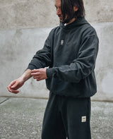 Blume Hoodie Schwarz von NKSP – seitlich am Model, kombiniert mit schwarzen Sweatpants